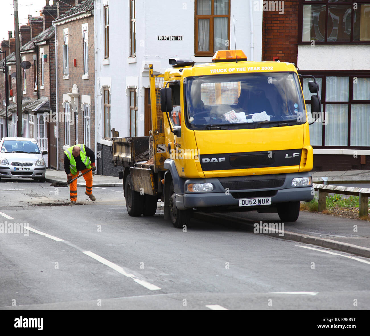 A council worker mending potholes in a road at Stoke-on-Trent, Staffordshire, England, UK Stock Photo