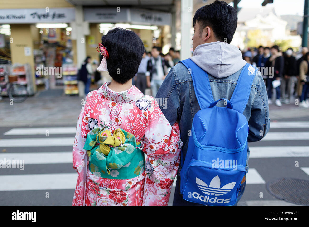 Young Japanese couple, woman dressed in traditional costume, waiting for crossing the street, Kyoto, Japan Stock Photo