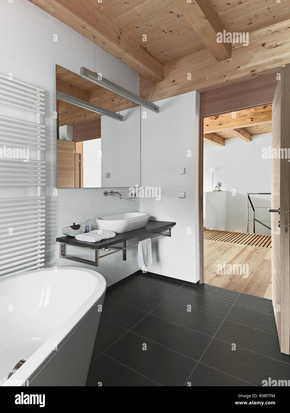 interiors shots of a modern bathroom with wooden ceiling in the foreground the bathtub and the counter top washbasin Stock Photo