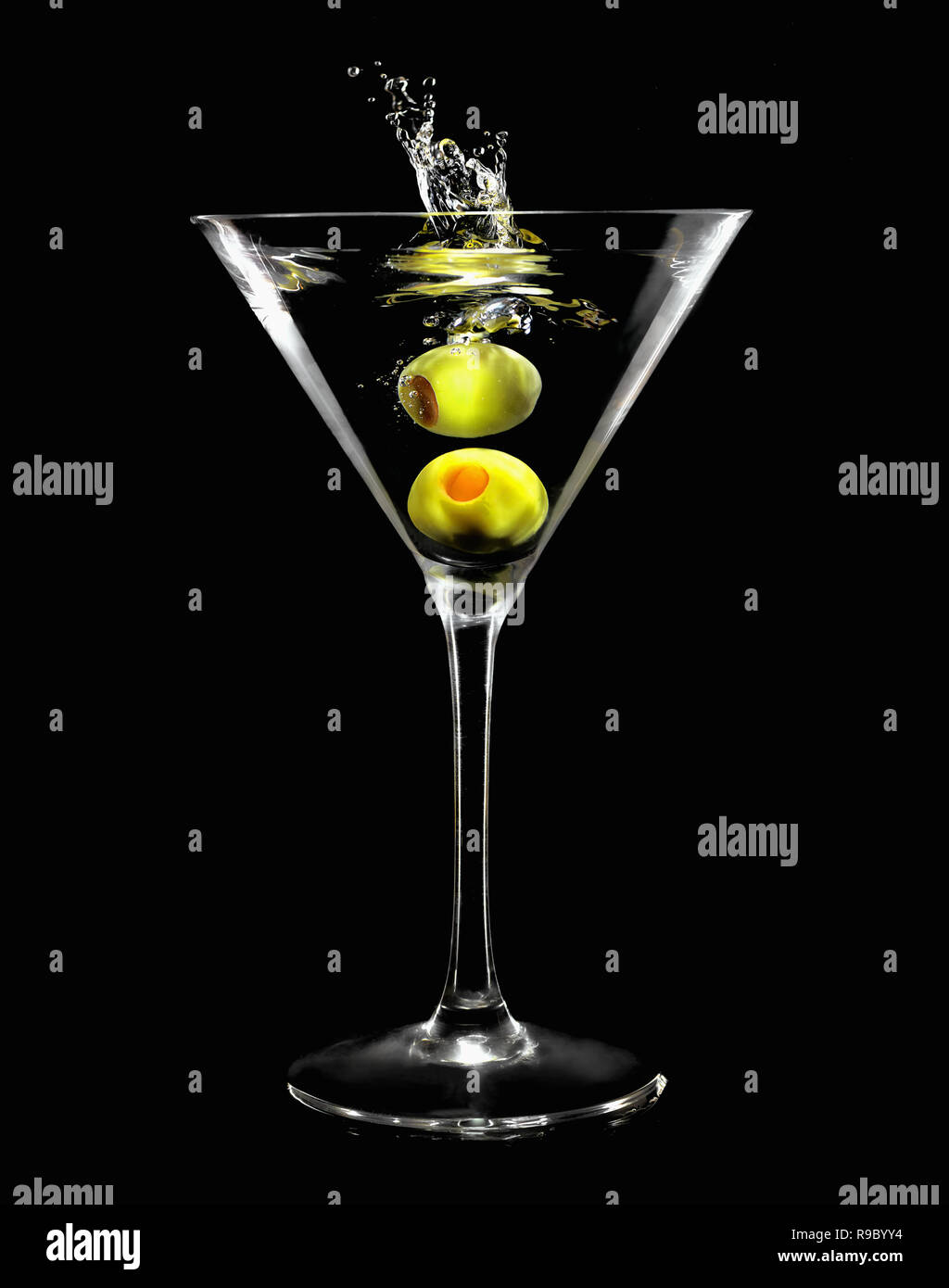 Splashing green olive in martini glass on black background Stock Photo