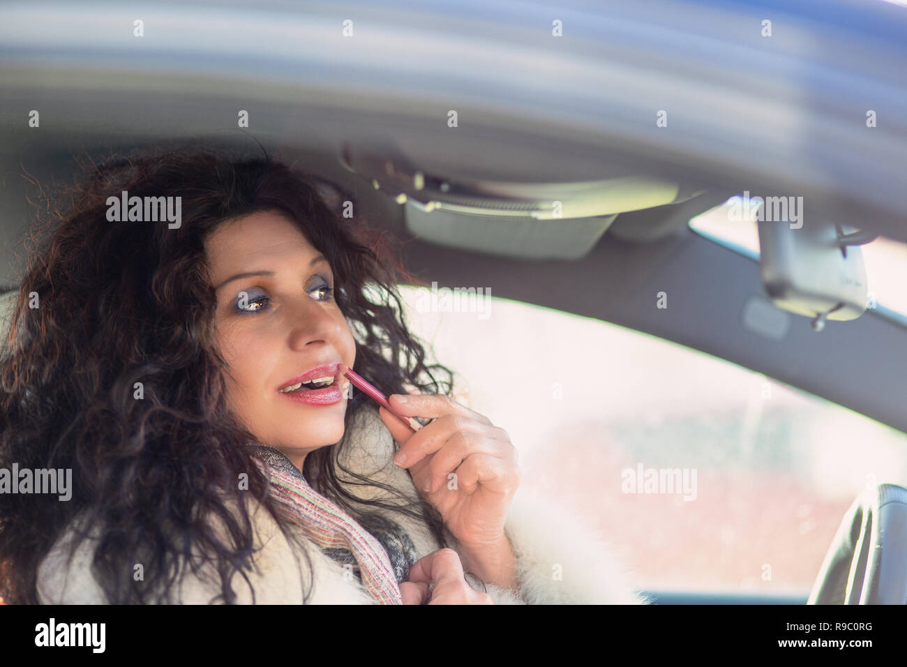 Girl Putting On Fresh Make Up At Mirror Drawing Lips With Pencil While Standing In A Car Stock Photo Alamy