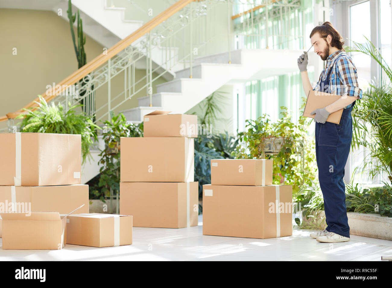 Pensive moving specialist counting delivered boxes Stock Photo Alamy