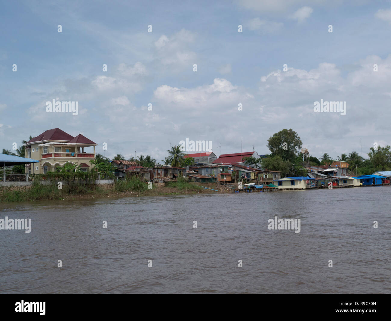 Cambodian village at side of Mekong River from ferry boat on journey from Chau Doc Vietnam to Phnom Penh Cambodia Asia Stock Photo