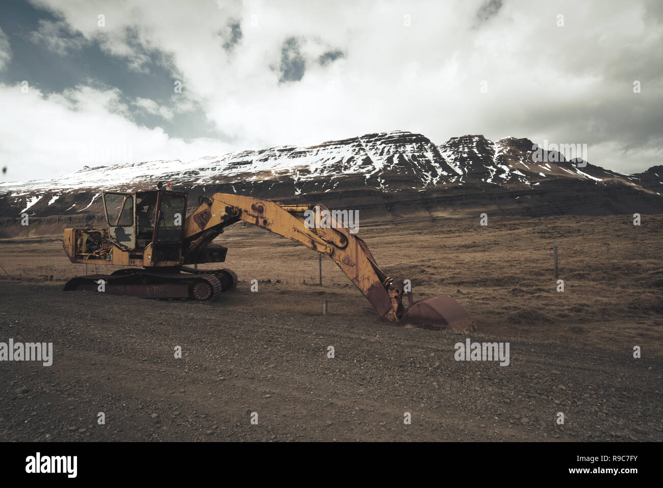 Old excavator wreckage in beautiful icelandic nature with gravel road and snow covered mountains in the background. Stock Photo