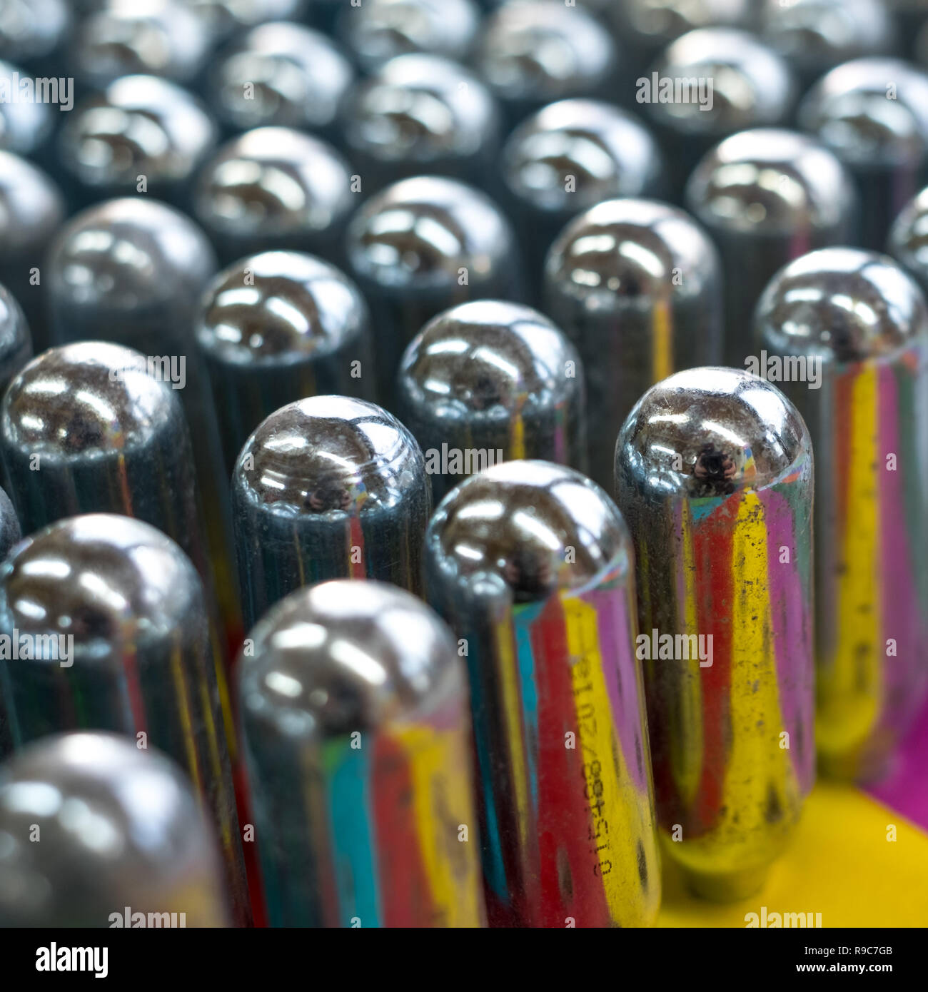 Empty nitrous oxide cannisters reflecting psychedelic colours metal