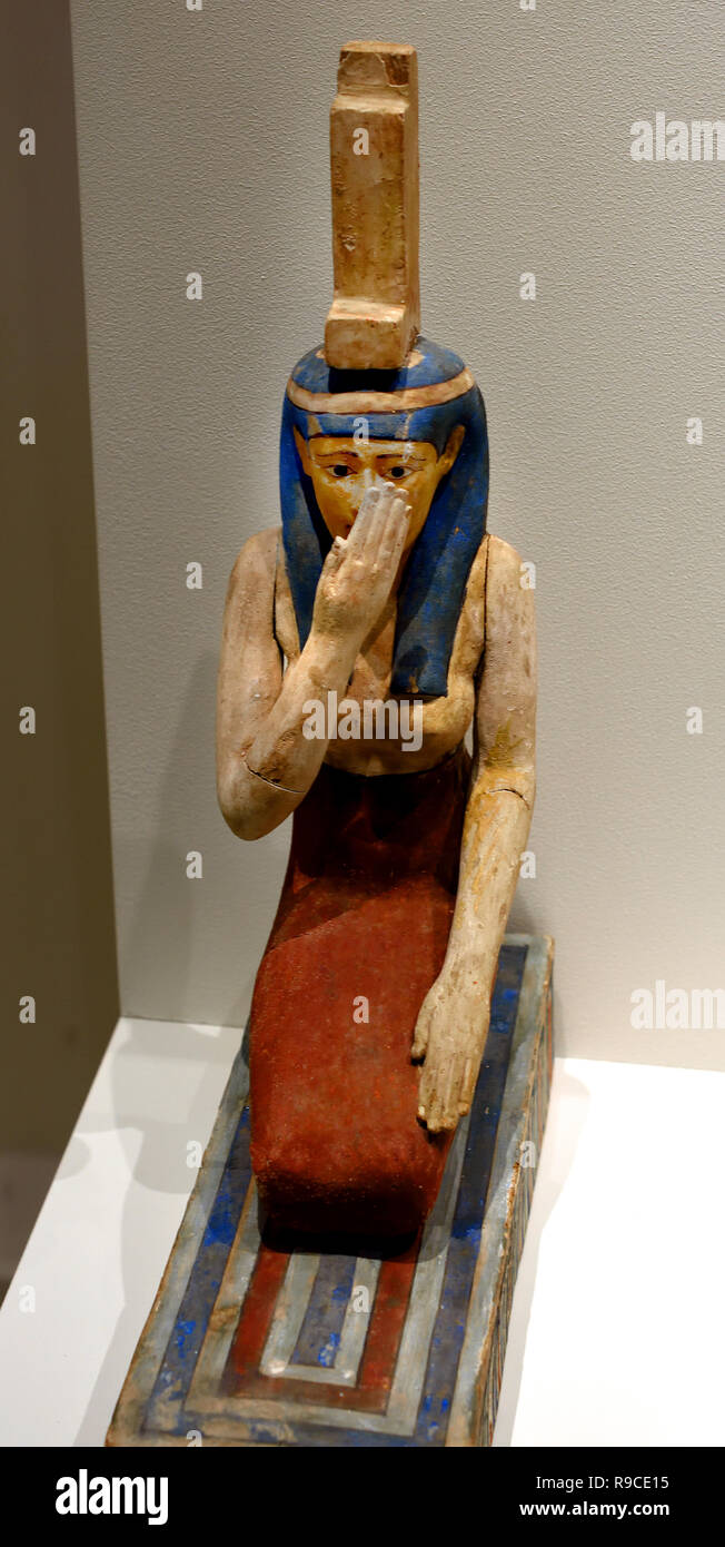 Goddess Isis Here we see the goddess Isis kneeling.)  With a hand in front of her face she wipes her tears. She is crying for her deceased husband, the god Osiris, Dimensions: height 40.5 centimetres, Material: wood, Period: Greek Period (about 300-200 BC), Middle Egypt, Egyptian. Stock Photo