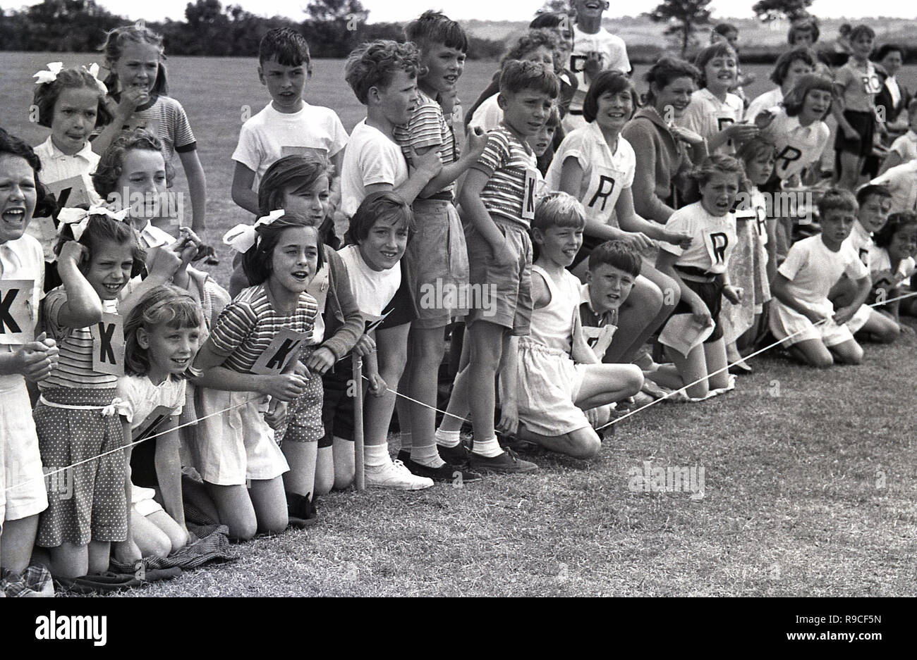 1950s, historical, school children in sitting on a grass field cheering