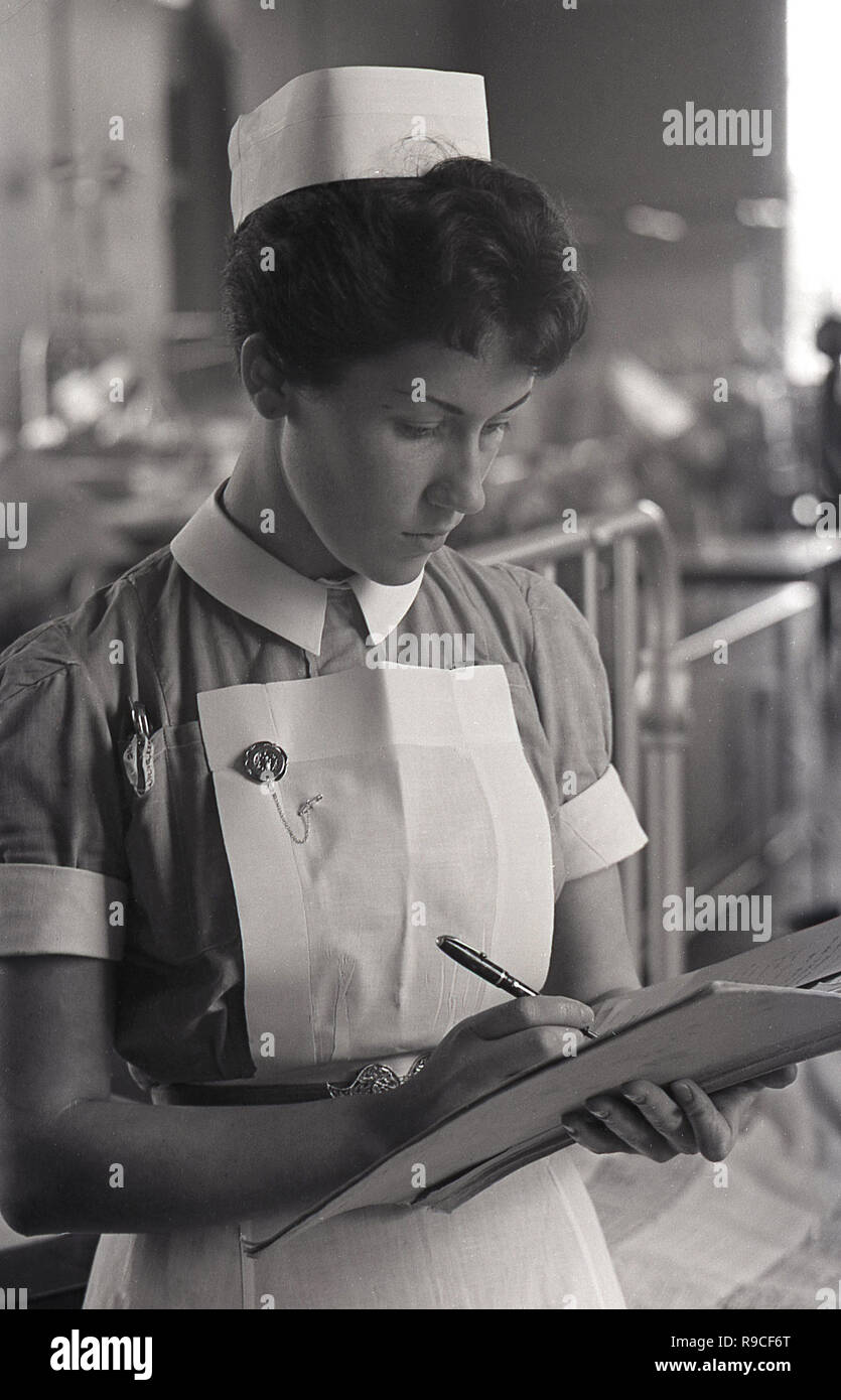 1955, historical, a female nurse at work on a ward writing notes on a patient's medical form, England, UK. Stock Photo