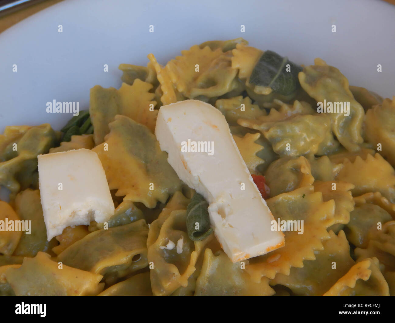 A dish of agnolotti with butter and sage in a dish with grated cheese   and two pieces of tuma ready to be eaten Stock Photo