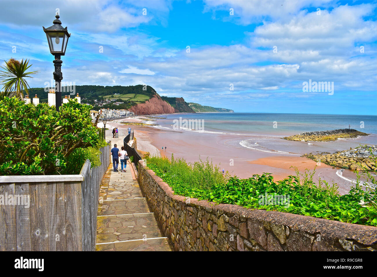 A couple walk down the coastal path leading to the picturesque seaside