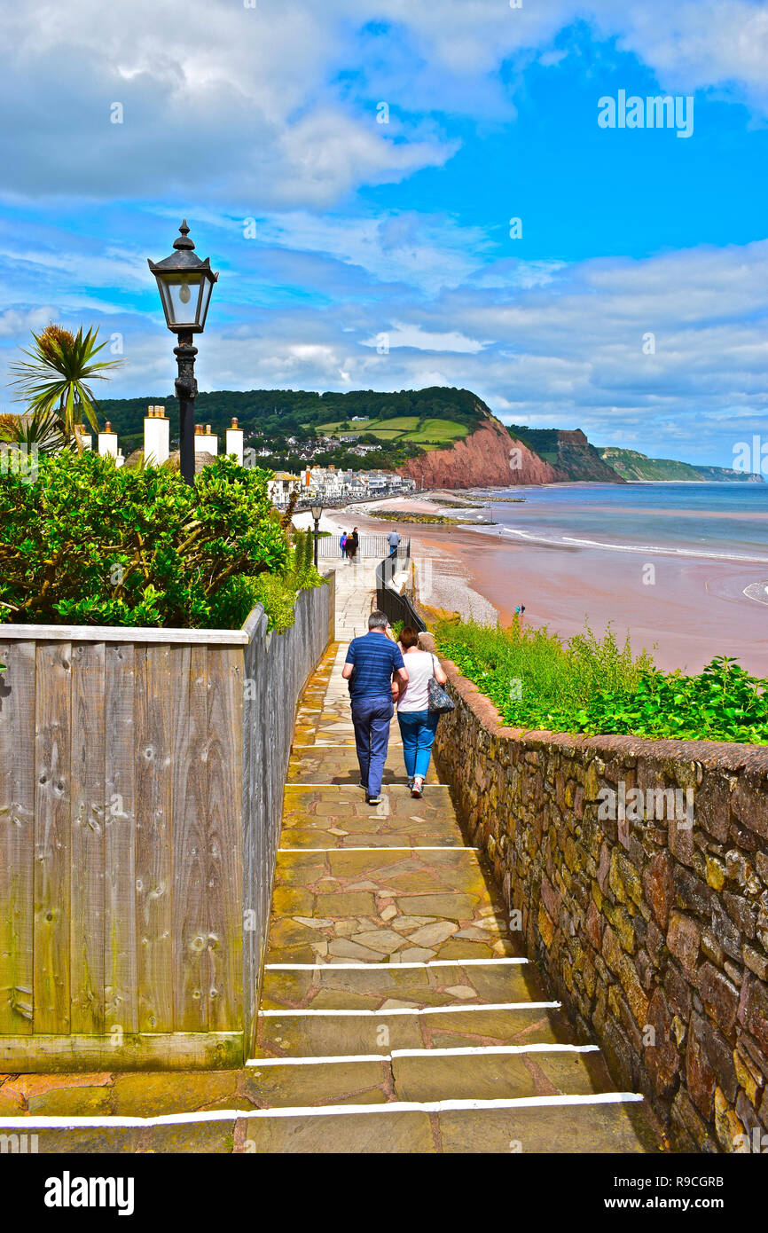 A couple walk down the coastal path leading to the picturesque seaside