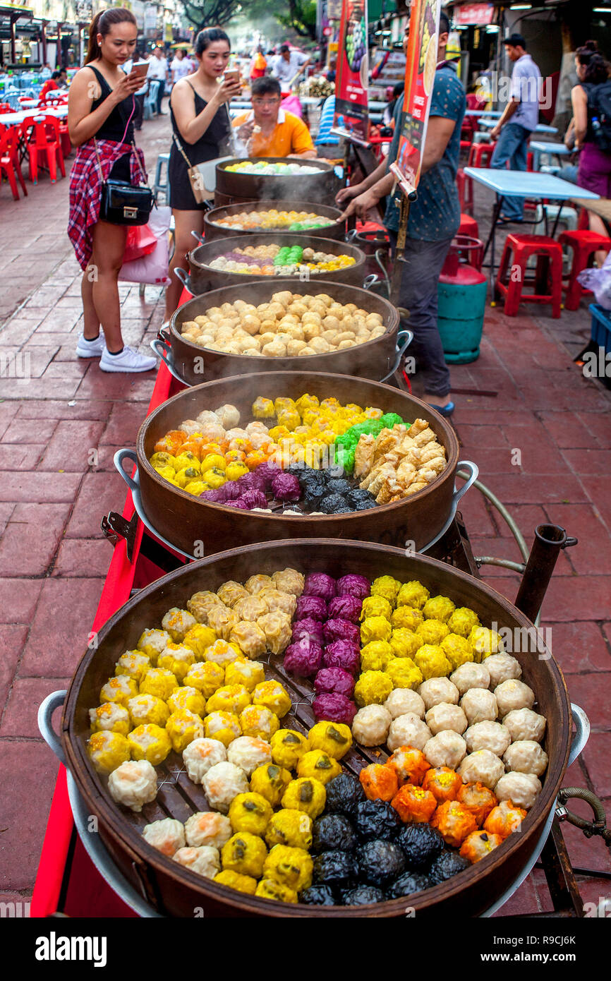 Street food vendor sells steamed Asain dumplings cooking in a wooden steamer on Jalan Alor, Food Street, in Bukit Bintang, Kuala Lumpur, Malaysia. Stock Photo