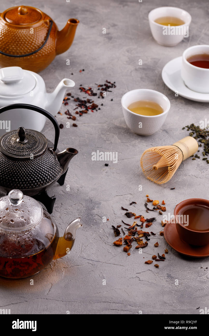 Tea card. Variety of teapots and cups on a gray background and different types of tea. Tea still life. Concept. Stock Photo