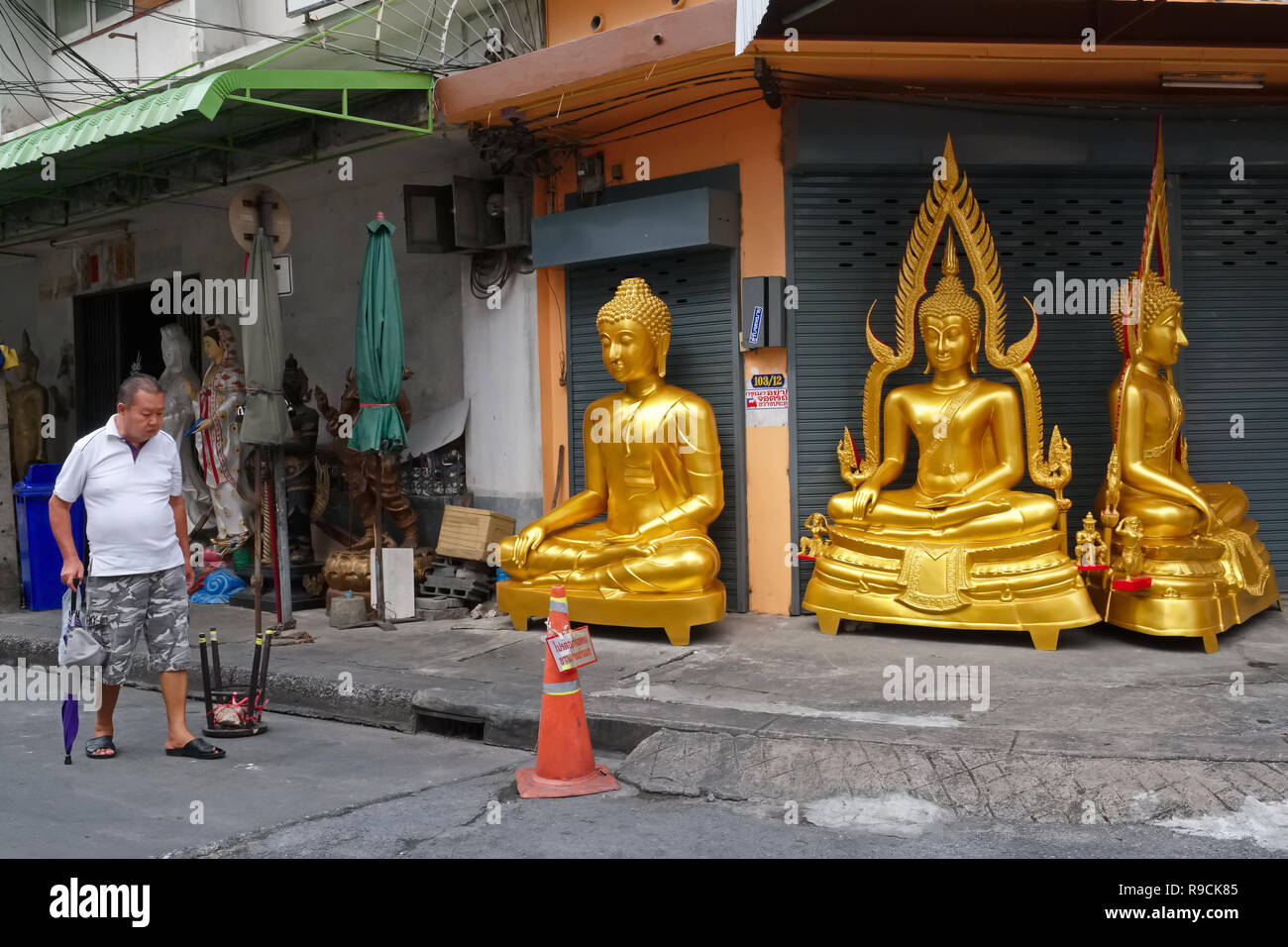 A man passes a factory for Buddha statues in Bamrung Muang Road, Bangkok, Thailand, a centre for the sale of religious objects Stock Photo