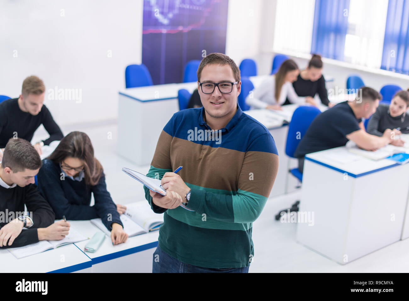 young male student with others writing notes in the classroom Stock Photo