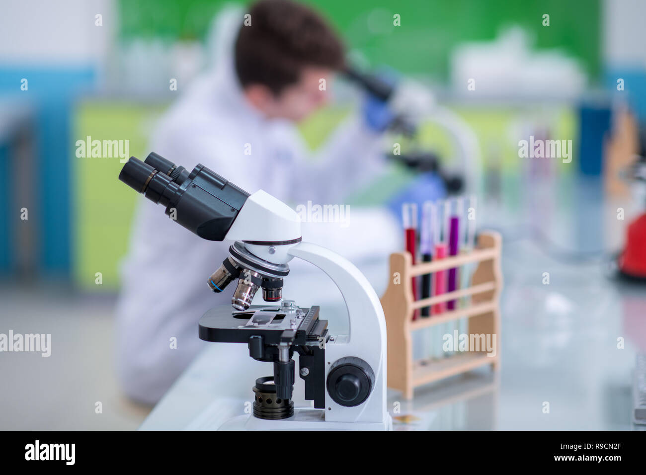 Young student scientist looking through a microscope while doing some research in the laboratory Stock Photo