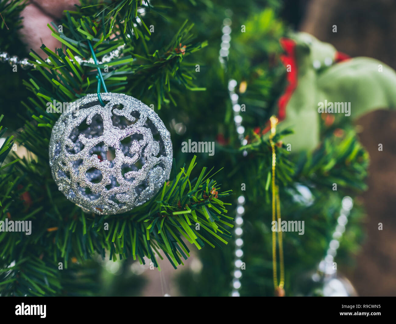 Christmas decoration background. Christmas carving glitter ball on green Christmas tree with copy space. Stock Photo