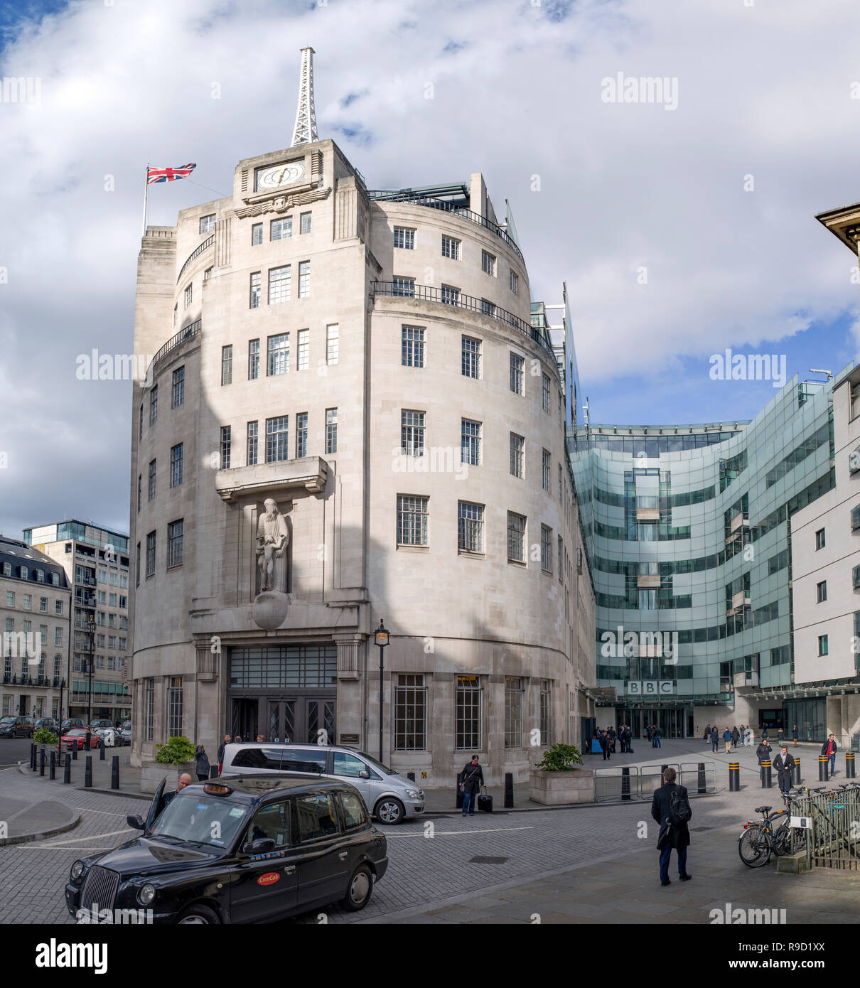 Exterior of BBC broadcasting House and the new Broadcasting House in central London, including stationary taxis and people crossing the courtyard. Stock Photo