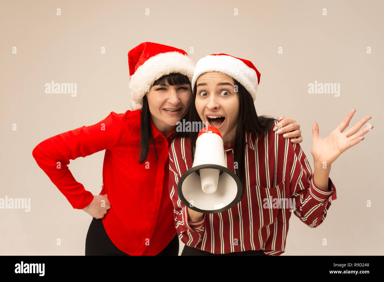 Happy family in Christmas sweater posing. Enjoying love hugs, holidays people. Mom and doughter on a gray background in the studio Stock Photo
