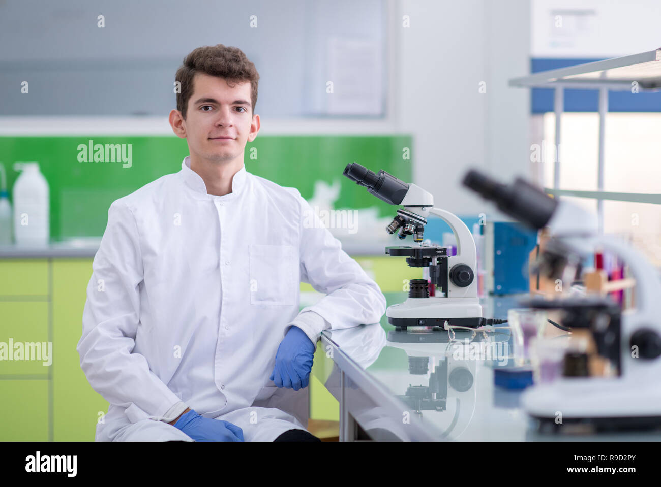 Young student scientist looking through a microscope while doing some research in the laboratory Stock Photo
