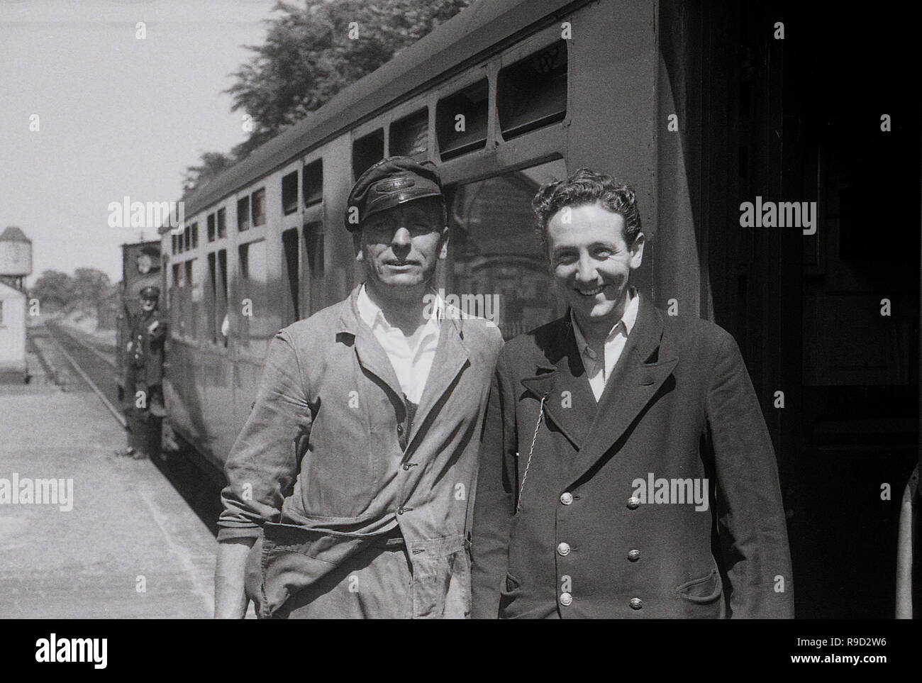 1950s, historical, two British Railways employees, a train driver of a steam locomotive in his cap and a train guard, stand together on a railway platform outside a train carriage, England, UK. British Railways was the state-owned company that operated overground rail transport from 1948 until 1997. In 1965 it became known as British Rail. Stock Photo