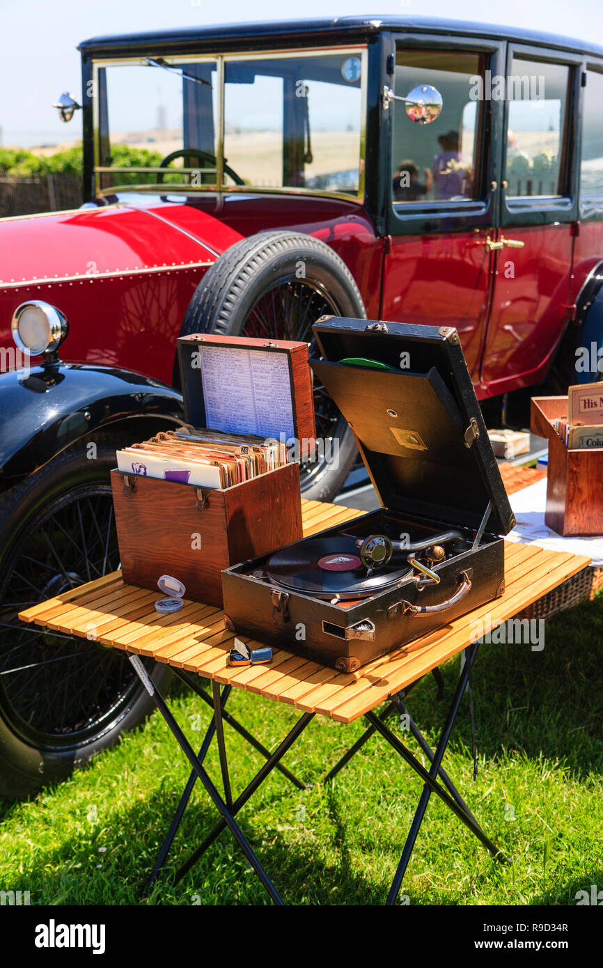 Vintage Phonograph with a meltrope 3 soundbox, next to box of 78 records on small folding table by a classic car, circa 1920s. Stock Photo