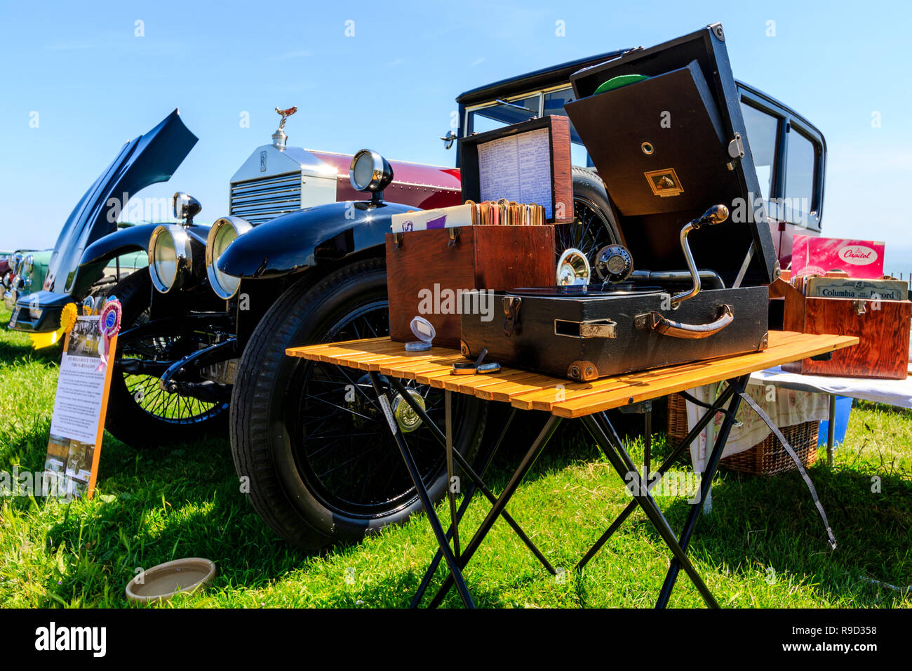 Vintage Phonograph with a meltrope 3 soundbox, next to box of 78 records on small folding table by a classic car, circa 1920s. Stock Photo