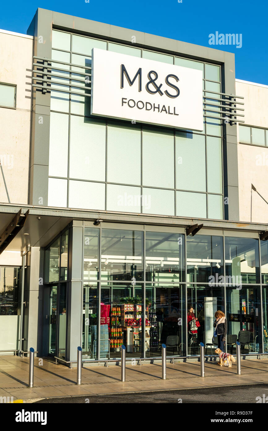 Westwood Cross shopping center, England. M&S store and food Hall entrance Wintertime, woman waiting outside with pet dog. Stock Photo