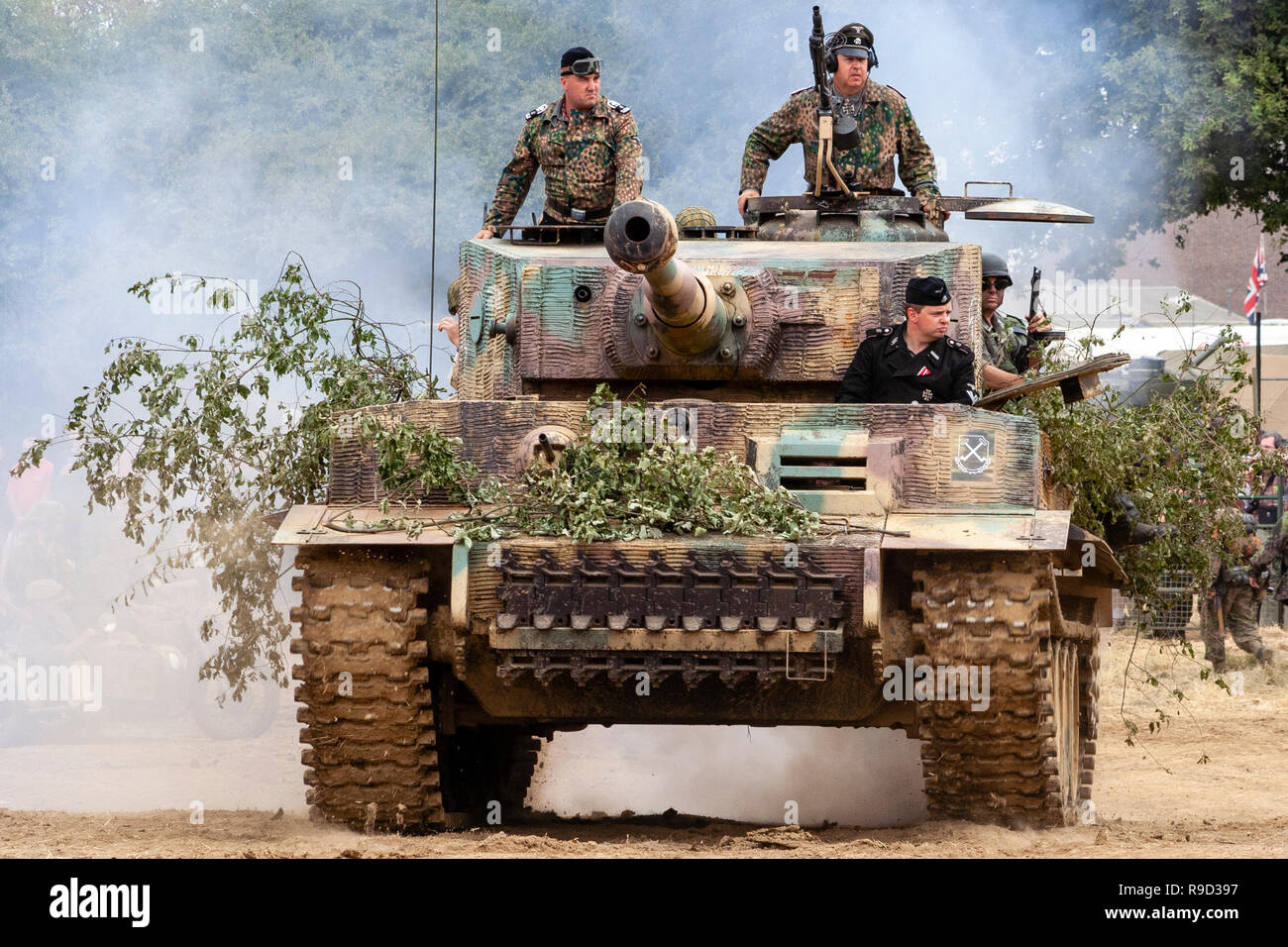 Re-enactment, War and Peace Show. German Tiger tank approaching at speed with tank commander in turret. Motion blur on tracks, dust behind tank. Stock Photo