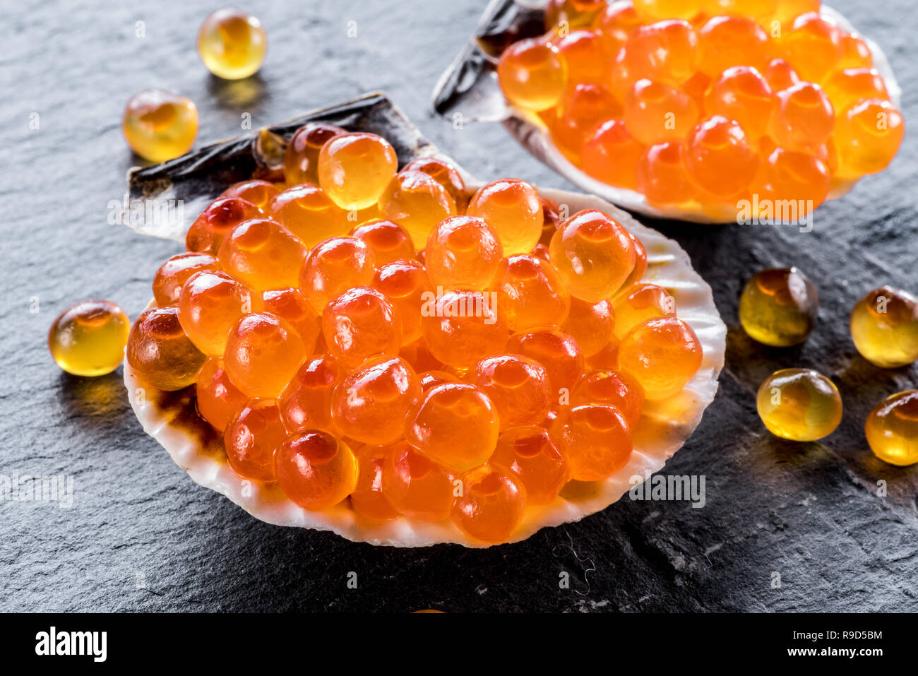 Caviar Shells Red caviar in the sea shells on gray graphite background. Macro picture ...