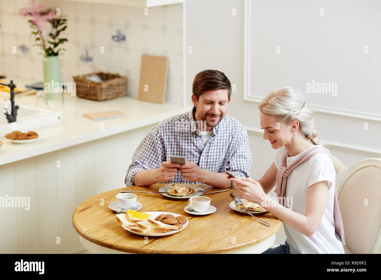 Cheerful couple sharing internet video at breakfast Stock Photo