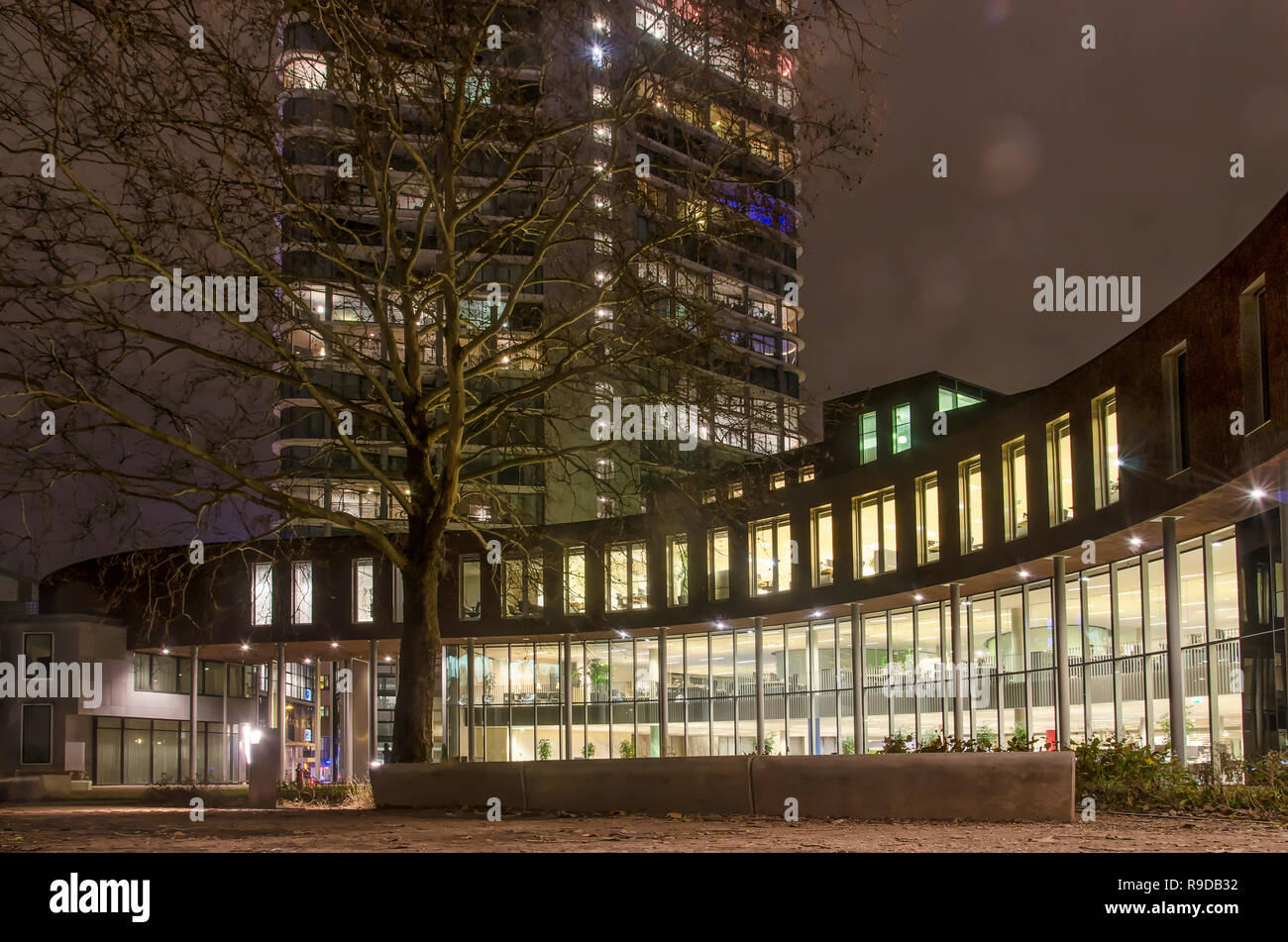 Eindhoven, The Netherlands, December 14, 2018: night view of offices around a courtyard off Smalle Haven, with the residential Vestada tower in the ba Stock Photo