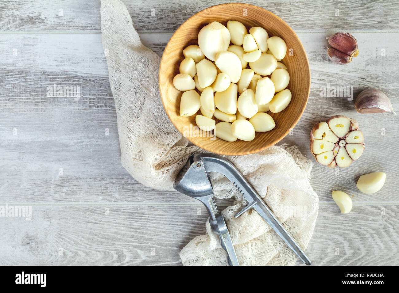 Fresh garlic heads, cloves set in plate on a light gray wooden surface