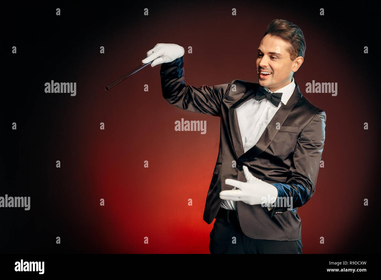 Professional showman wearing suit standing isolated on black and red ...