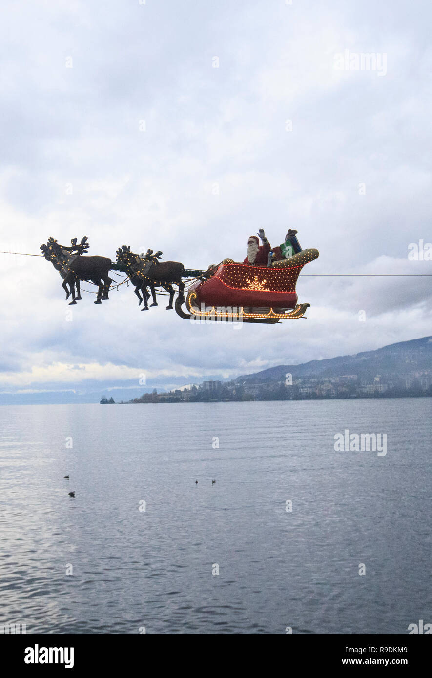 Montreux, Switzerland. 22nd Dec, 2018. A 'Santa Claus' waves to the crowd from his flying sleigh drawn by 'reindeers' over Lake Leman at sunset in Montreux, Switzerland, on Dec. 22, 2018. The flying Santa Claus stunt show is part of promotional activities by the Christmas market in Montreux, which is one of the most famous and biggest markets of its kind in Switzerland. Credit: Xu Jinquan/Xinhua/Alamy Live News Stock Photo
