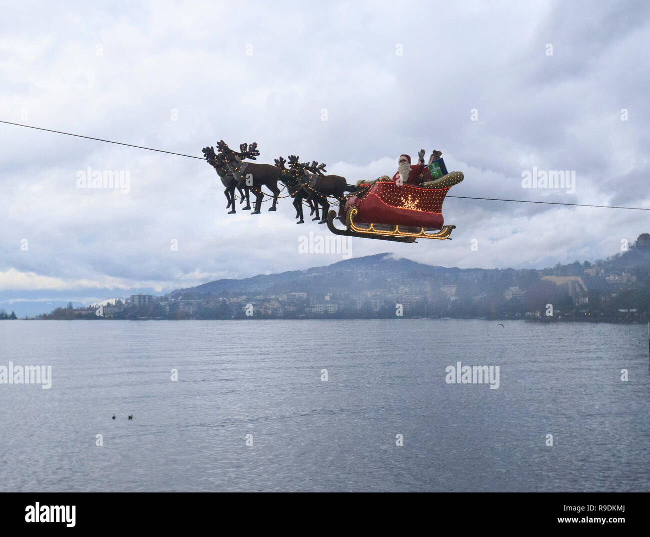 Montreux, Switzerland. 22nd Dec, 2018. A 'Santa Claus' waves to the crowd from his flying sleigh drawn by 'reindeers' over Lake Leman at sunset in Montreux, Switzerland, on Dec. 22, 2018. The flying Santa Claus stunt show is part of promotional activities by the Christmas market in Montreux, which is one of the most famous and biggest markets of its kind in Switzerland. Credit: Xu Jinquan/Xinhua/Alamy Live News Stock Photo