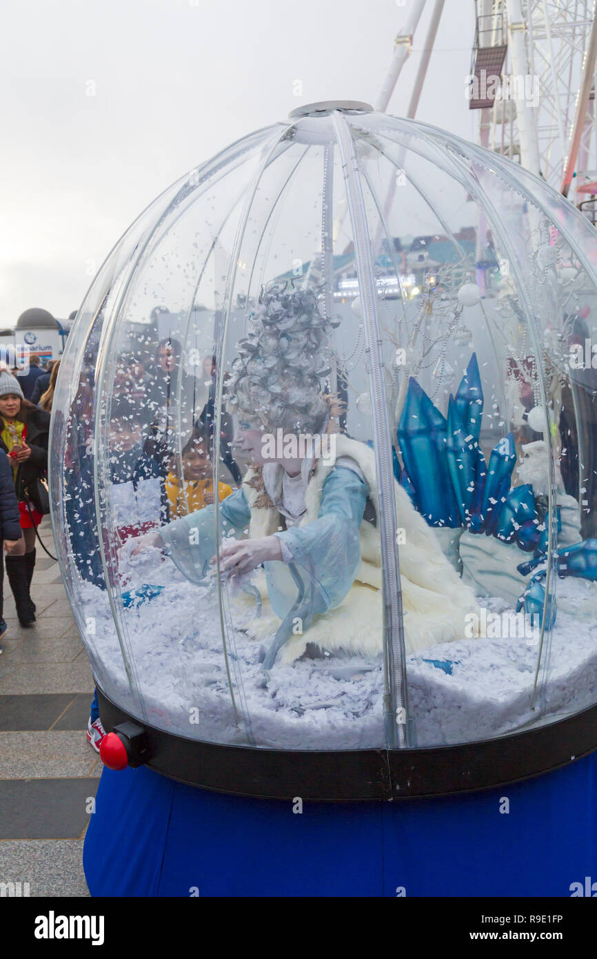 Bournemouth,  UK. 23rd December 2018. Children are fascinated by the human snowglobe with the beautiful snow queen encased in her snow blizzard, as she gracefully glides along enchanting visitors young and old. Credit: Carolyn Jenkins/Alamy Live News Stock Photo