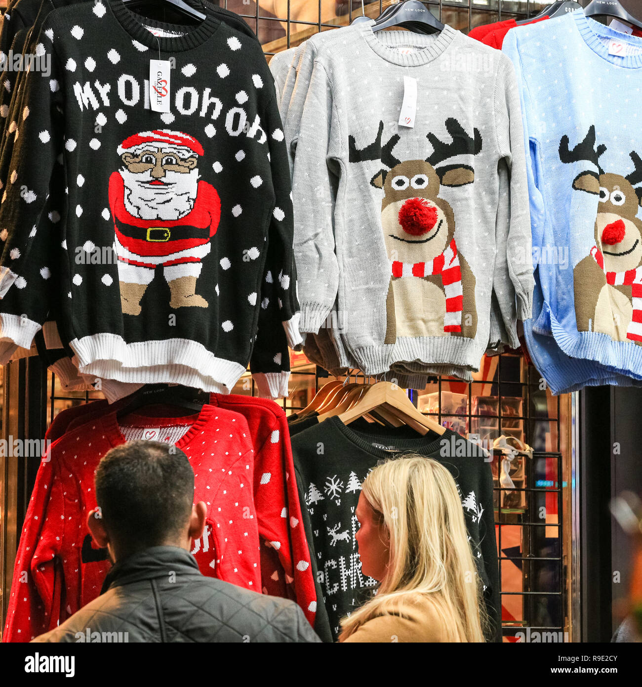 London, UK. 23rd Dec 2018. A couple browse Christmas jumpers. Shoppers with  last minute purchases rush through the sales in the West End of London on  the Sunday before Christmas, taking in