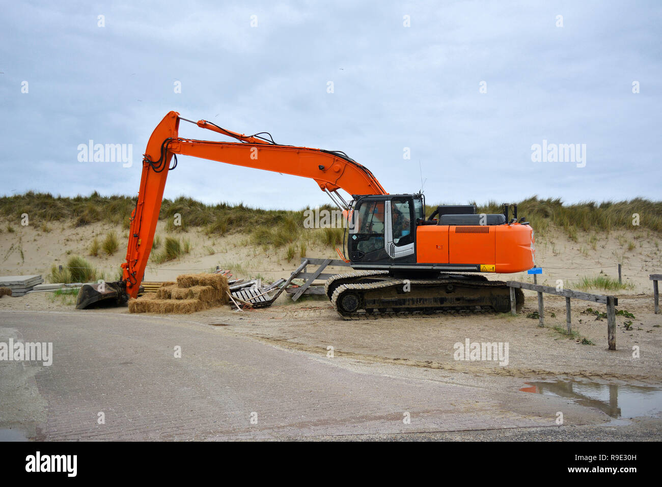 Excavator vehicle for building up sand at beach at Paal 9 after a heavy storm in Texel, Netherlands Stock Photo
