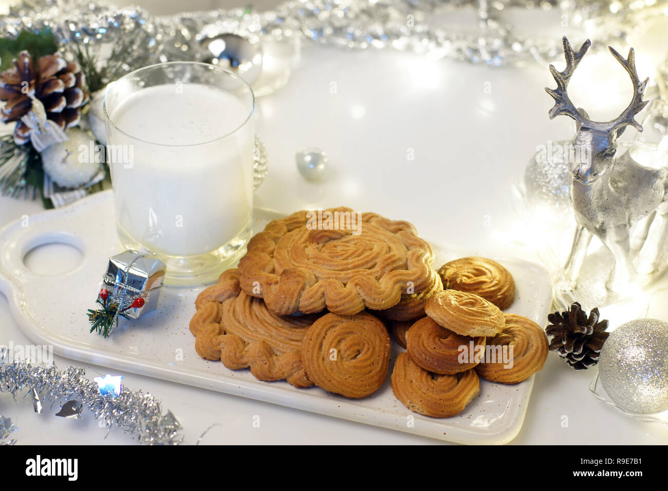 Gingerbread cookie and milk for Santa on a tray on a decorated table for Christmas with a deer, a garland and tinsel Stock Photo