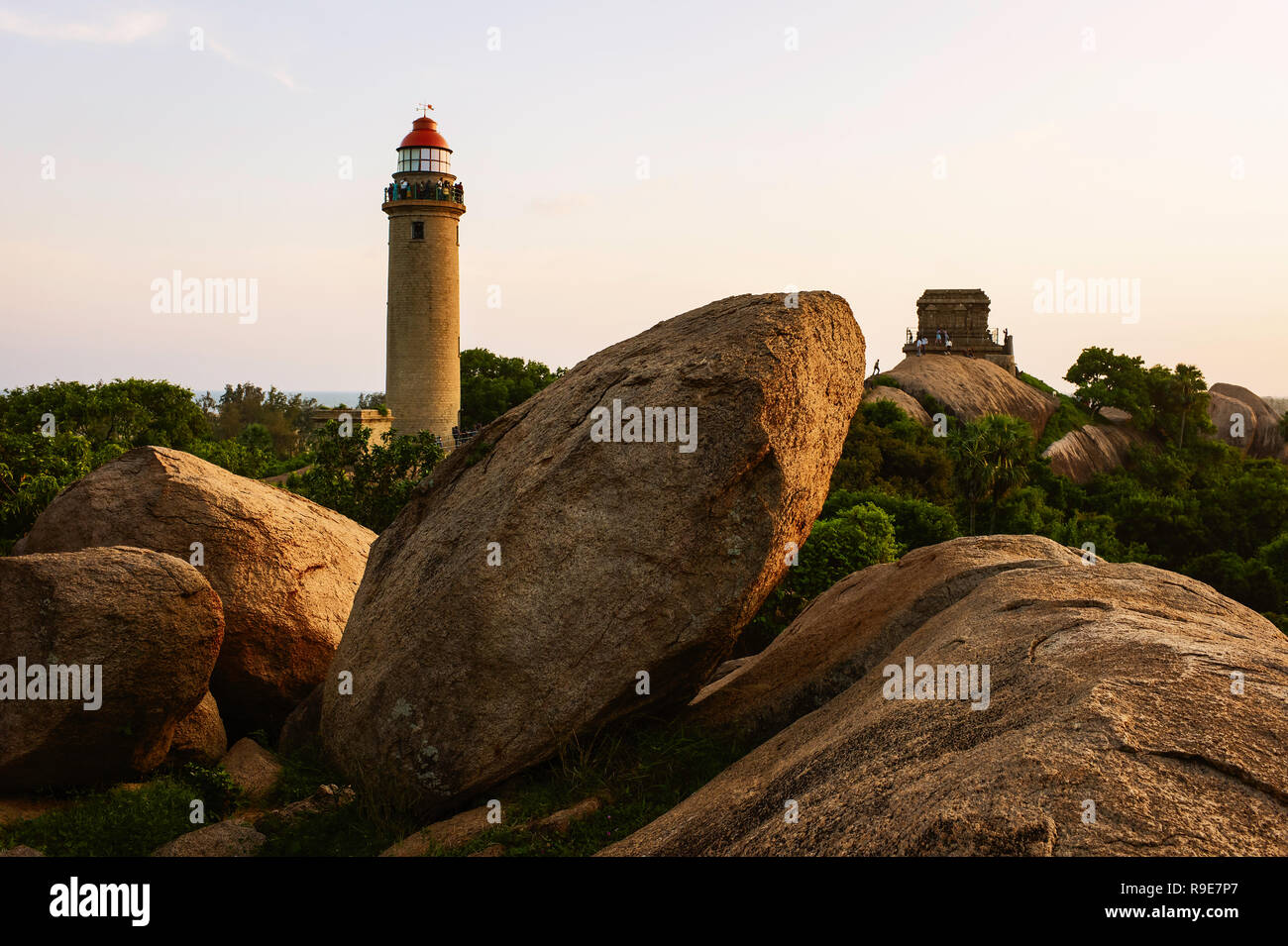 Ancient boulders and trees surround the modern lighthouse and ruins of the old lighthouse at dusk, Mamallapuram, Tamil Nadu, India. Stock Photo