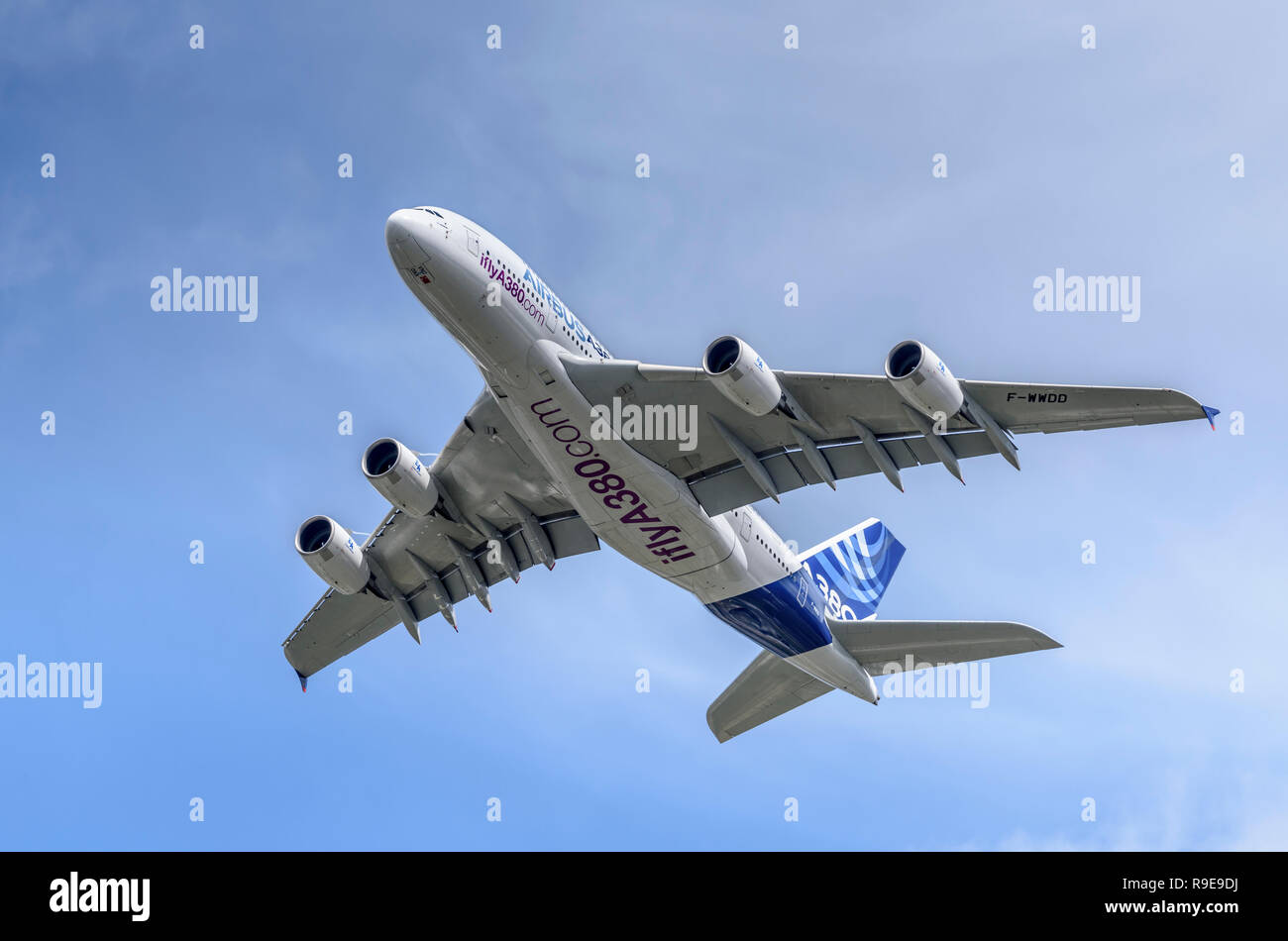Airbus A380 passenger airliner shows its underside and flight control surfaces during a clean pass from right to left. Stock Photo
