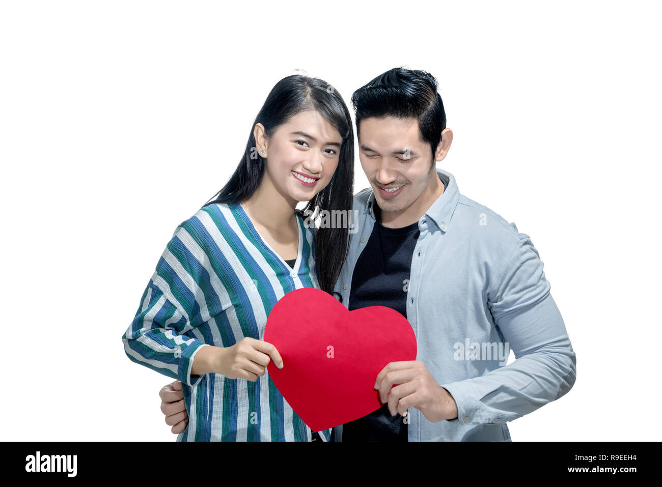 Happy asian couple holding red heart together standing isolated over ...