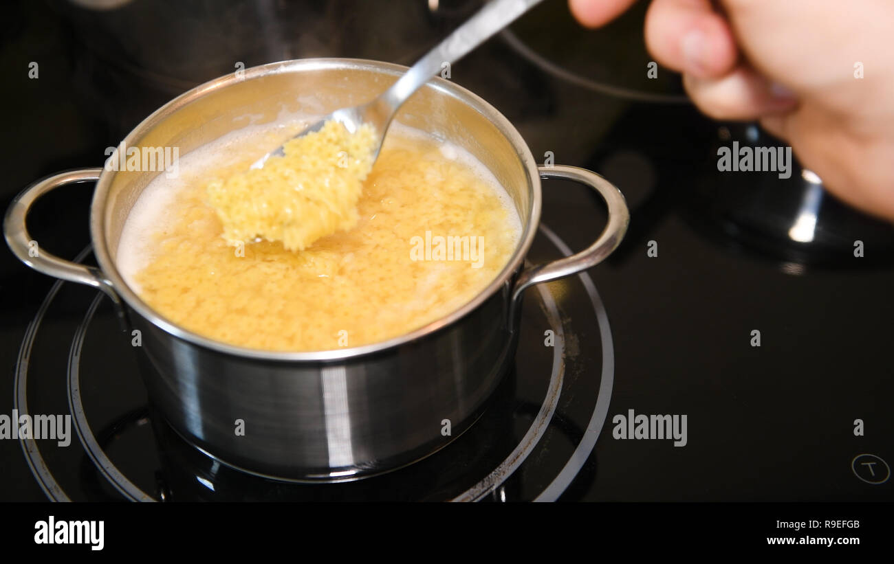 Close up cooking traditional soup noodles, flower shaped noodles boiling in water Stock Photo