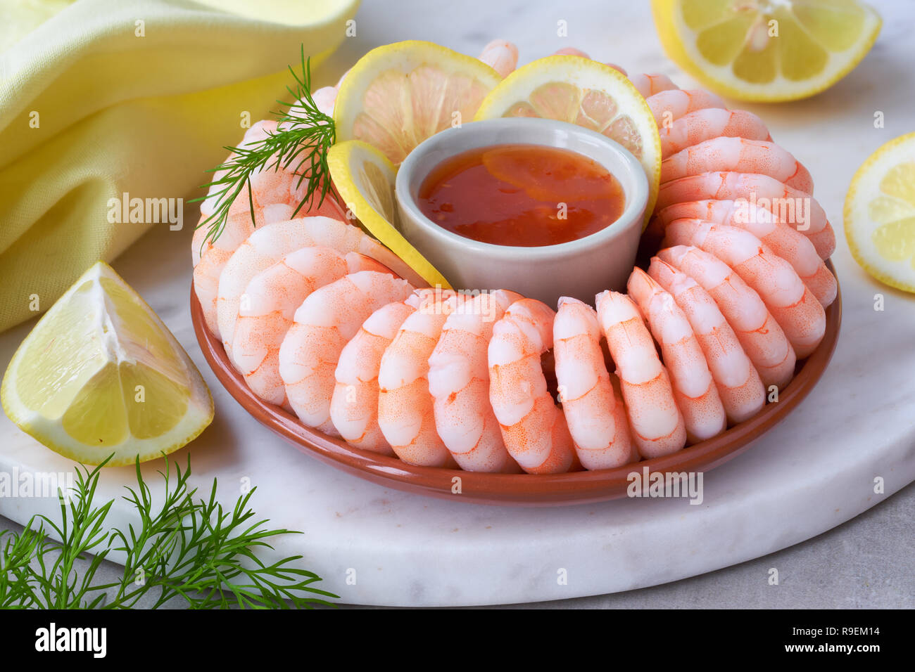 Close-up on shrimp ring with sweet chili sauce on marble serving board with yellow towel on light background Stock Photo