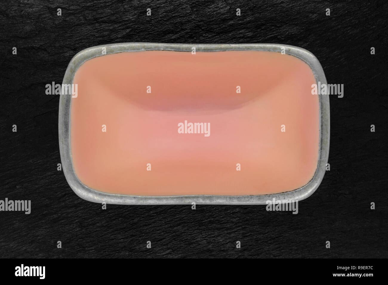 Top view of rectangular pink empty dish with silver edges on black stone background Stock Photo