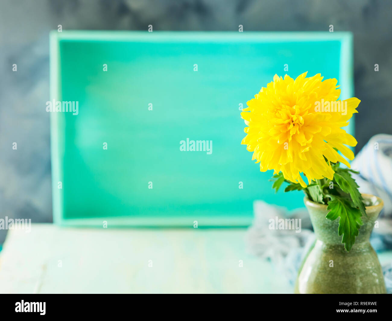 Turquoise Pastel Color Background With Yellow Flower In Vase