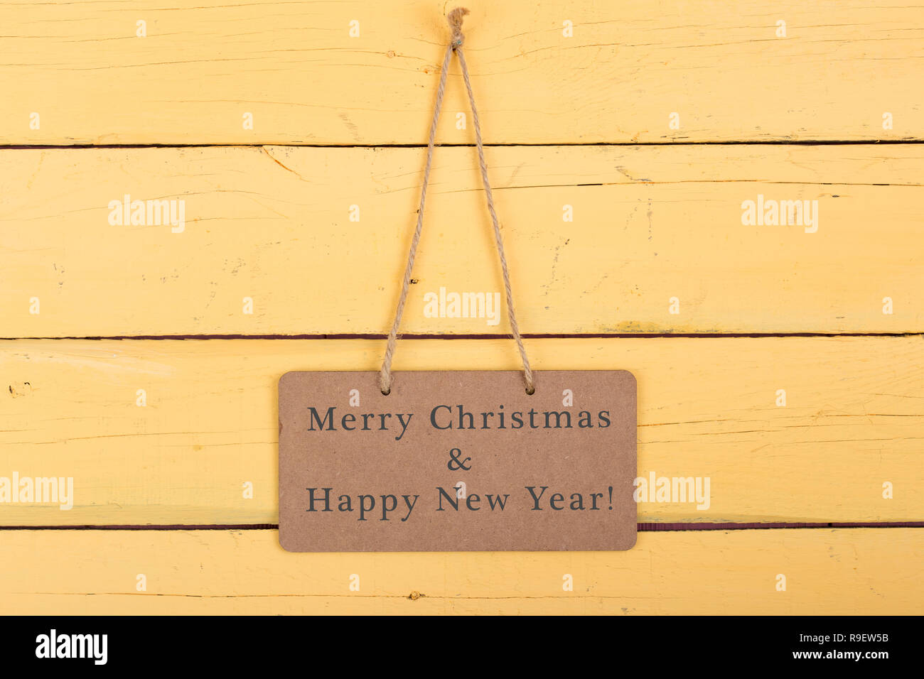 Blackboard with text 'Merry Christmas & Happy new year' on yellow wooden background Stock Photo