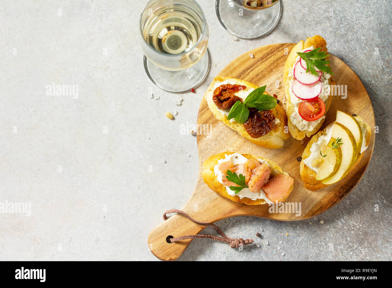 Italian Antipasti snacks set for Wine. Brushetta with Soft Cheese, Pear,  Radish, Salmon and Dried Tomatoes on a light stone background. Top view  flat Stock Photo - Alamy