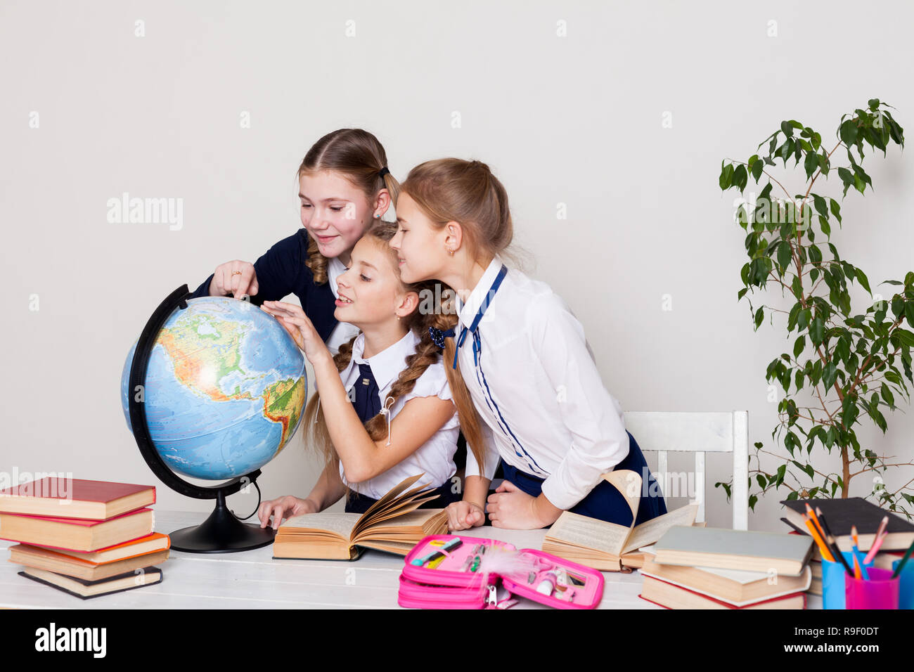 three girls in the classroom studying geography globe of planet Earth ...